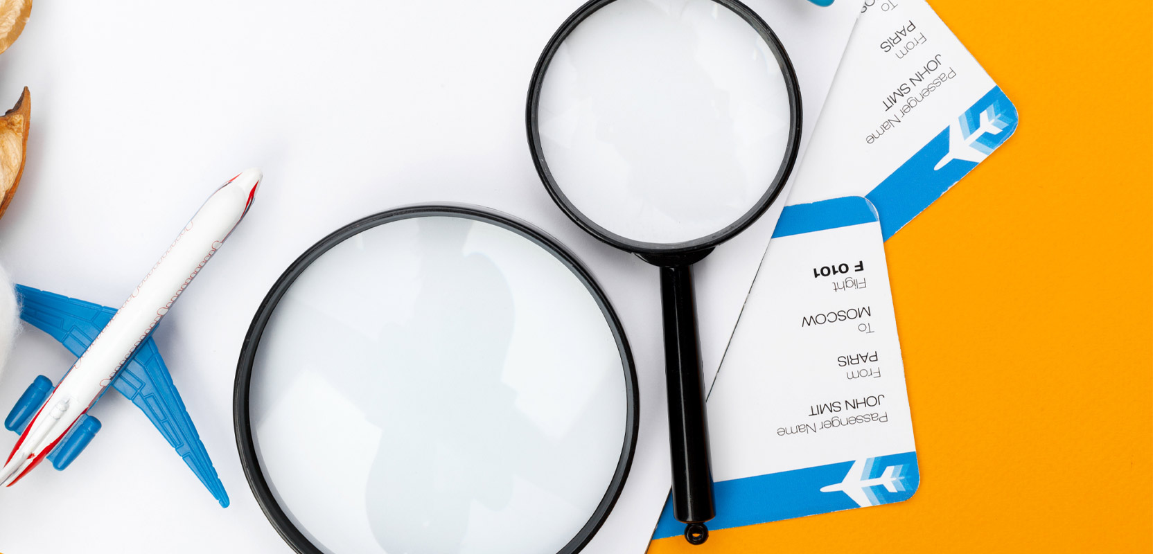 Magnifying glasses next to a model plane and airline tickets representing a stay-at-home travel agent side hustle
