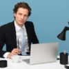 Professional consultant in a suit looking thoughtful and sitting at a white desk with a laptop and mug