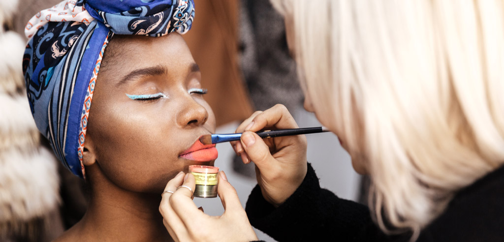 Freelance makeup artist applying bright makeup to a client 