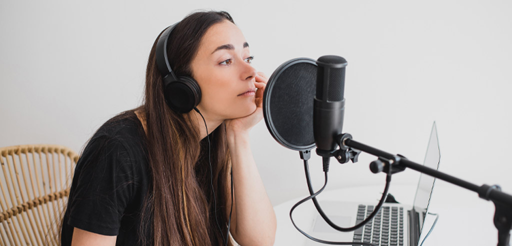 Voice actor sitting in a chair and leaning into a microphone while considering what to say