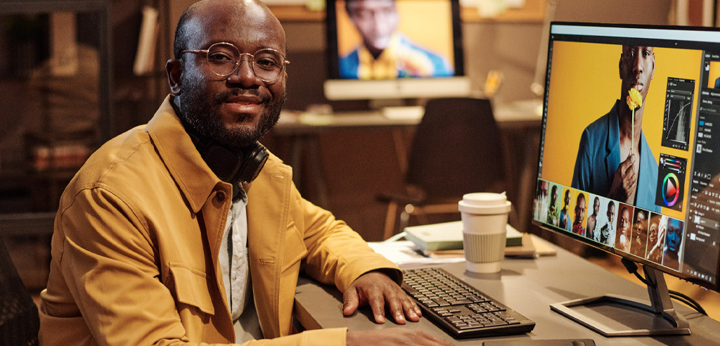 Graphic designer sitting at a computer working on his side hustle