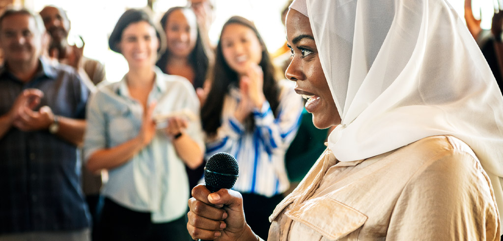 Freelance motivational speaker with a microphone addressing an applauding crowd