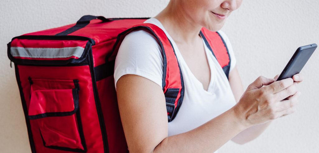 DoorDash driver standing indoors looking at her phone