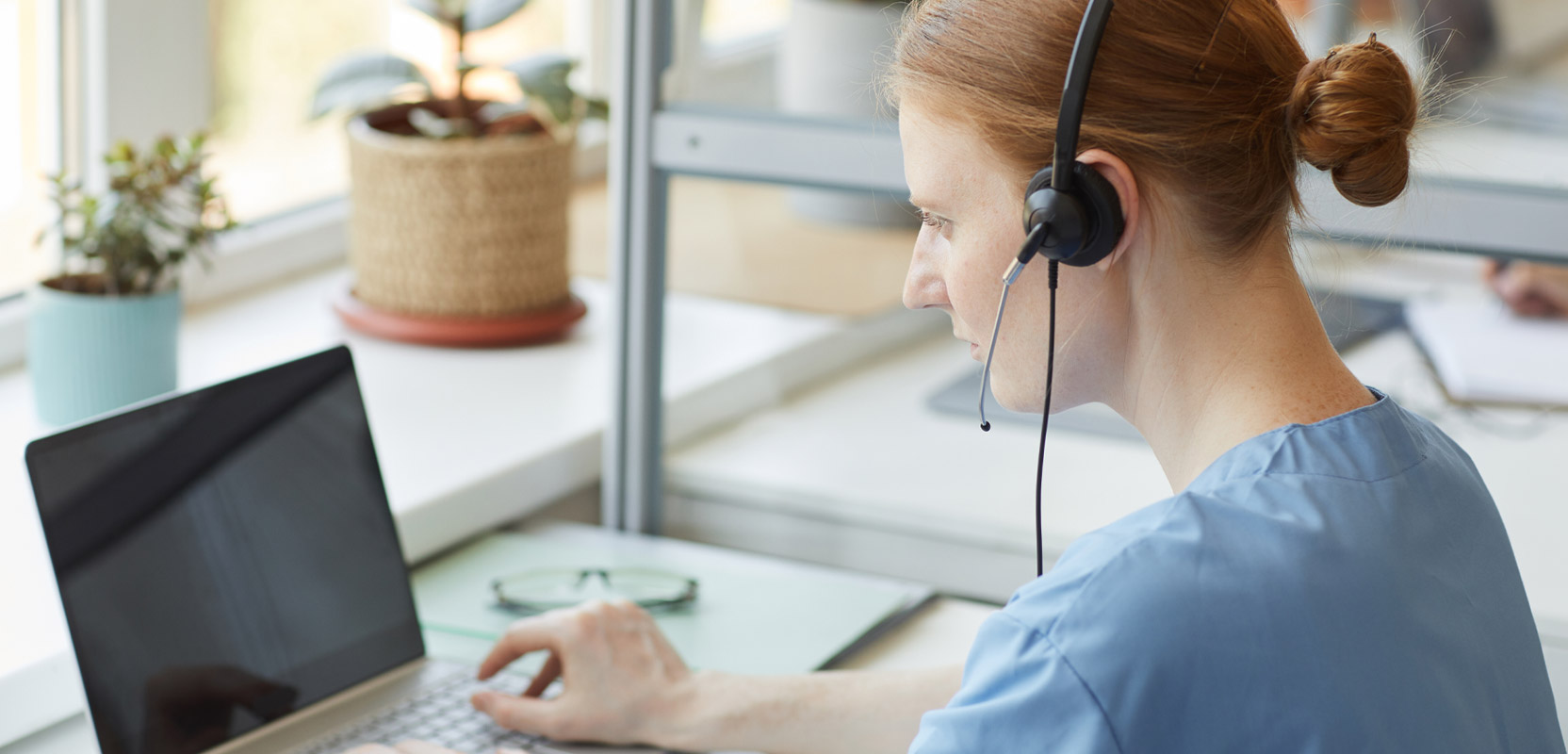 Freelance transcriptionist listening to headphones and typing at a laptop