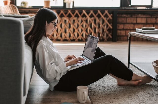 A woman working on a computer in her living room.