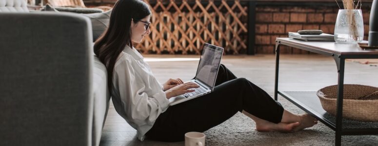 A woman working on a computer in her living room.