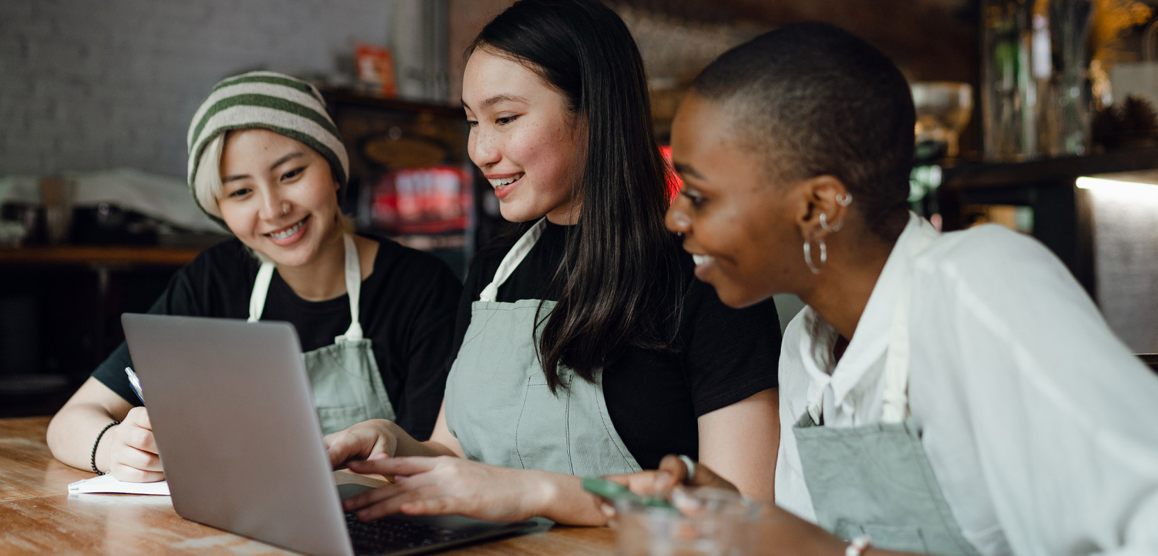 Small business owners sitting at a table and collaborating on a freelance article on a laptop